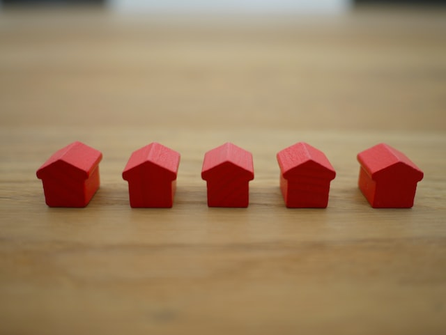 Five red monopoly houses in line on a table